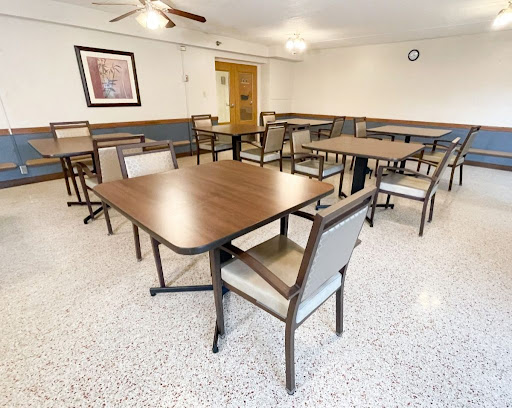 A spacious dining area featuring several tables and chairs, designed for communal gatherings.