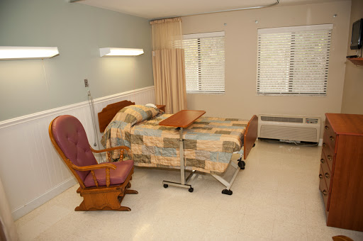 A hospital patient room featuring a bed, a chair, and a wheelchair.