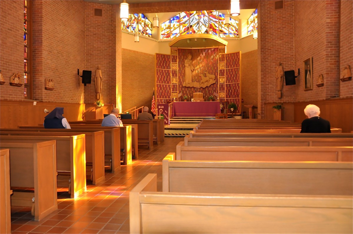 A serene church interior with wooden pews and a stained glass backdrop.