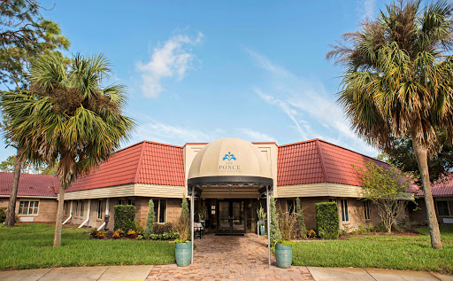 A welcoming entrance with palm trees and a clear blue sky.