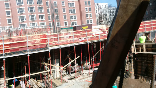 A view of an active construction site with scaffolding and workers in an urban environment.