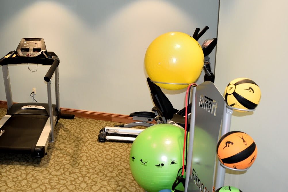 Gym with exercise equipment and colorful emoticon balloons.