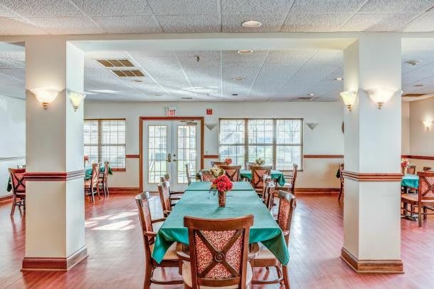A well-lit dining area with neatly arranged tables and chairs, adorned with floral centerpieces.