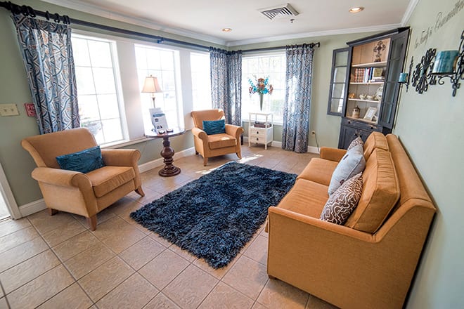 A cozy living room with a sofa, armchairs, and a blue rug.