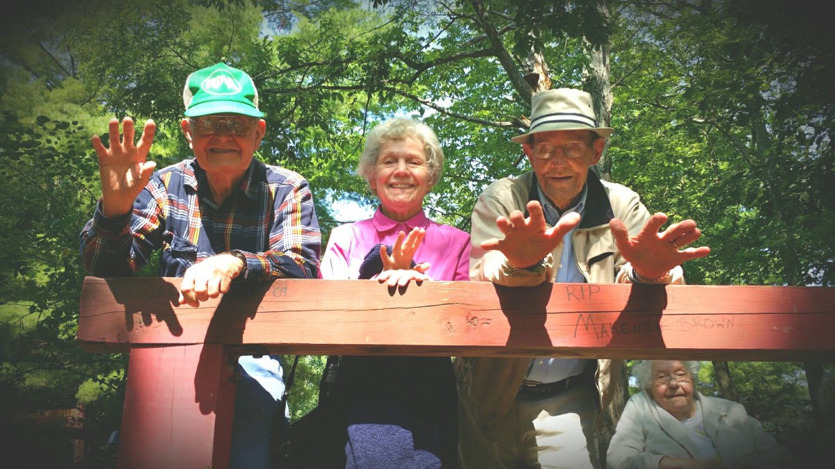 Three seniors enjoying a day outdoors on a wooden platform.