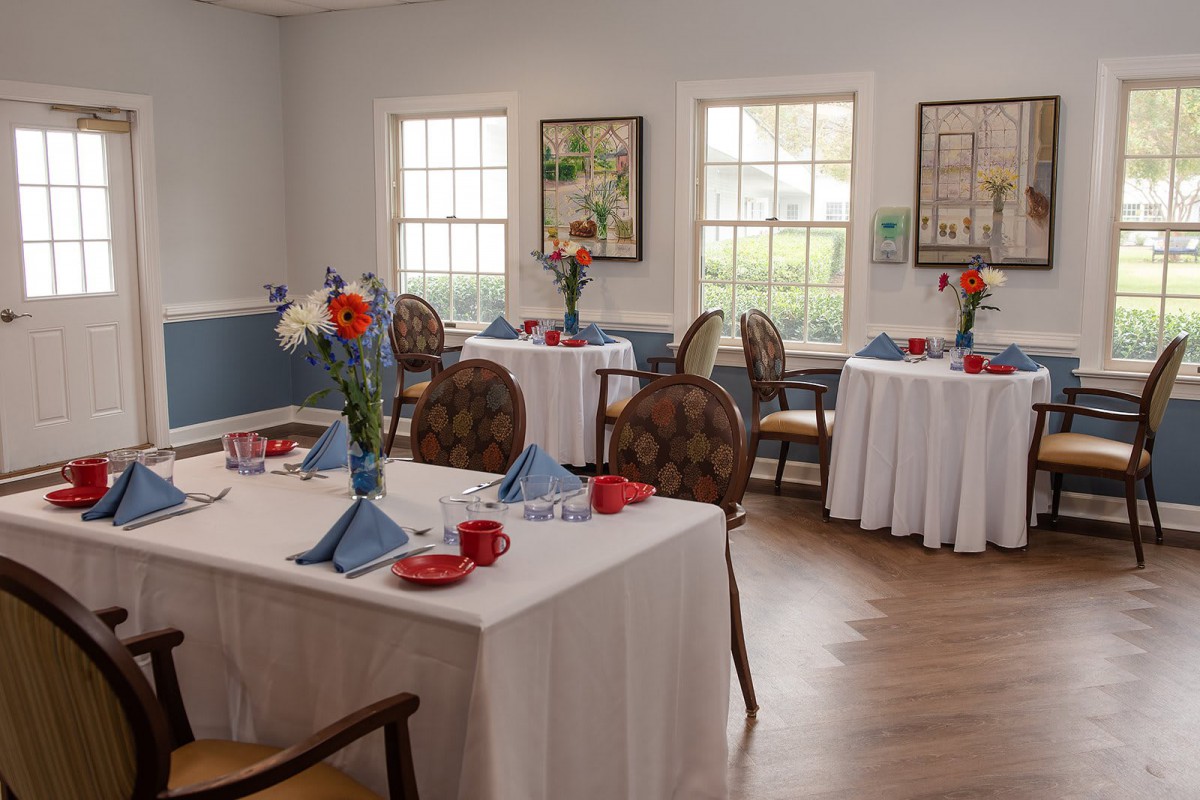 A cozy dining room with elegantly set tables and floral arrangements.