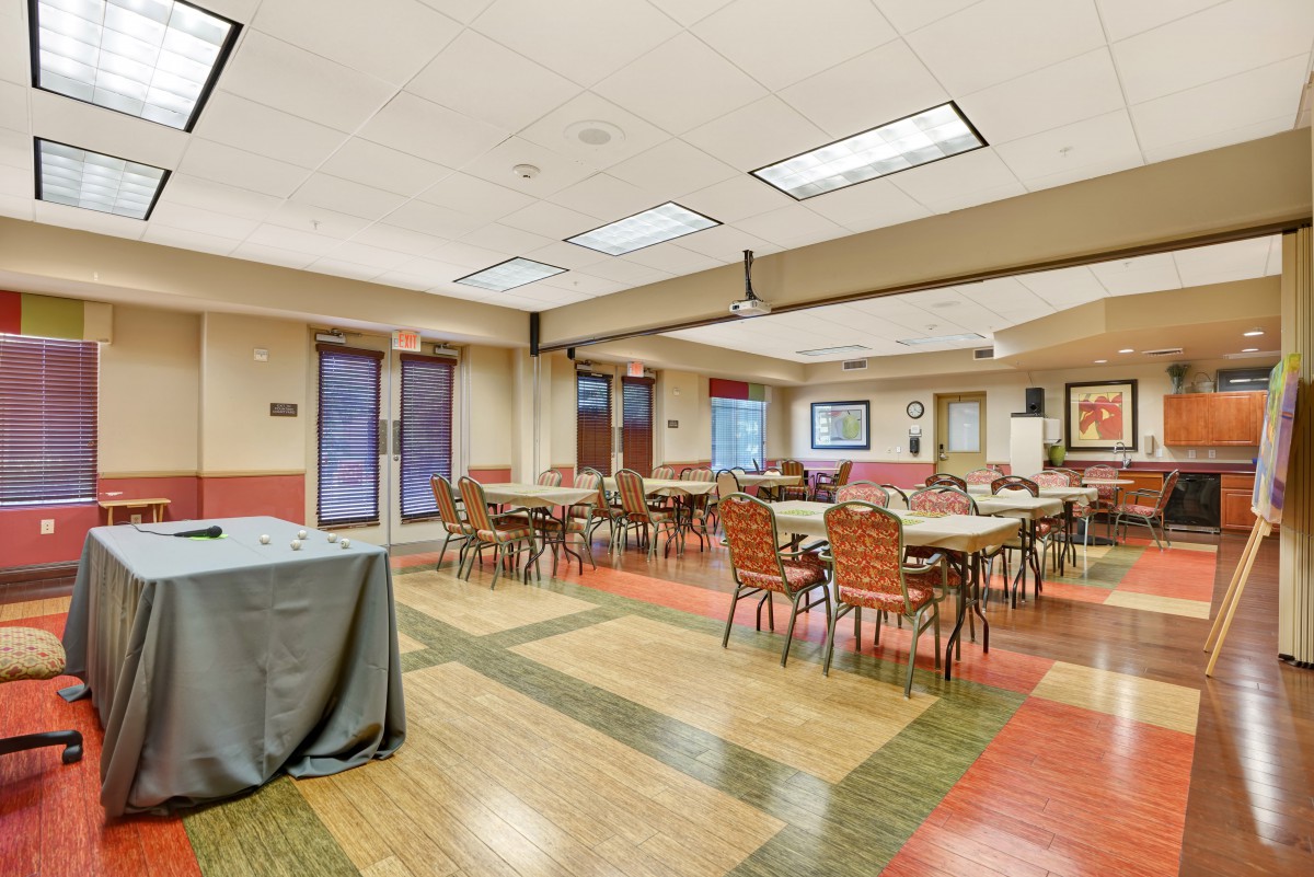 An empty indoor dining room with tables and chairs arranged neatly, suitable for meetings or gatherings.
