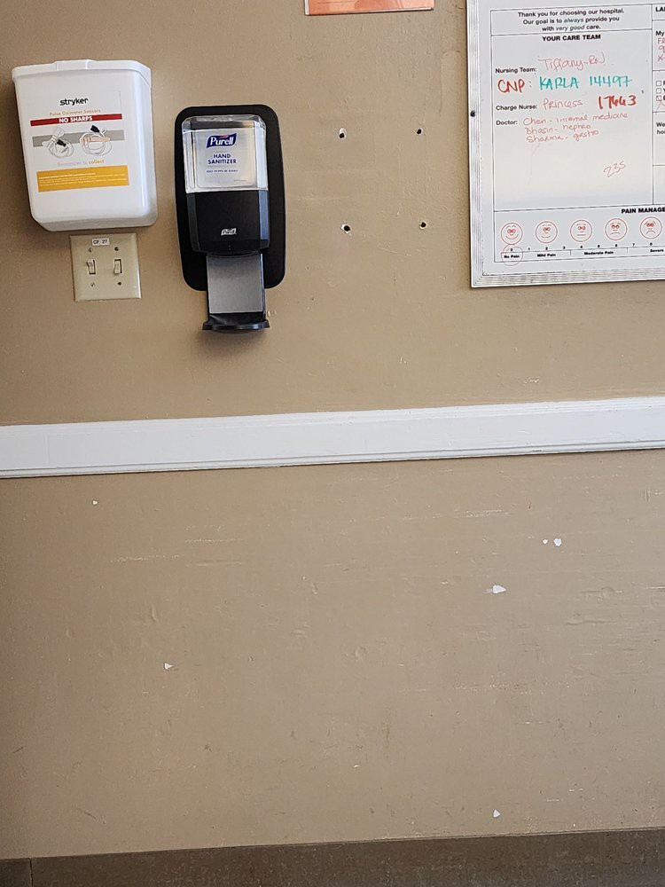 A wall-mounted hand sanitizer dispenser next to a bulletin board.