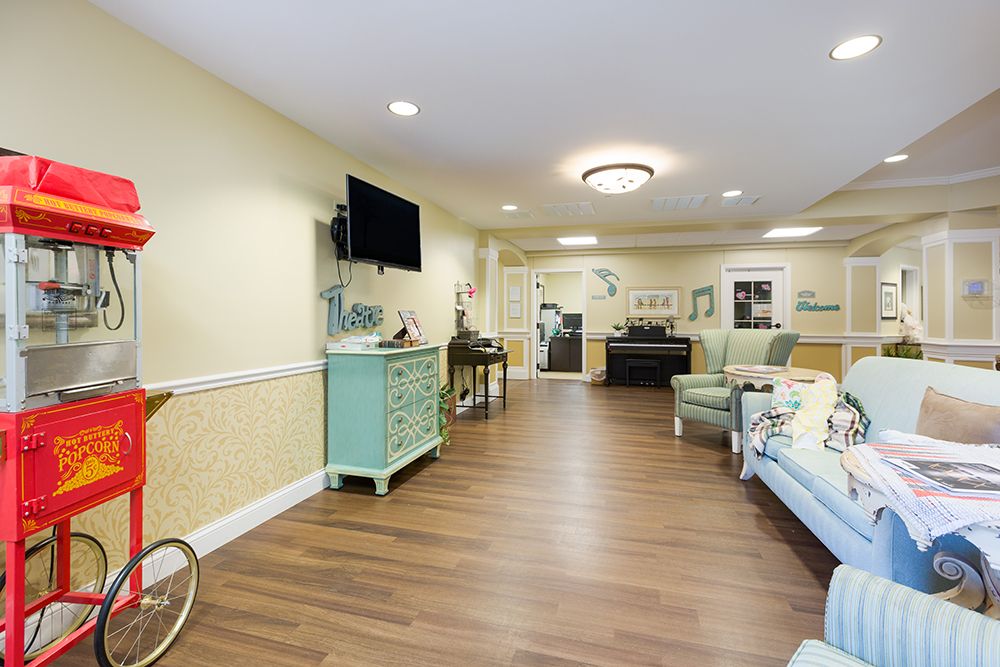 A cozy living room with wooden flooring, featuring comfortable seating and a mounted TV.