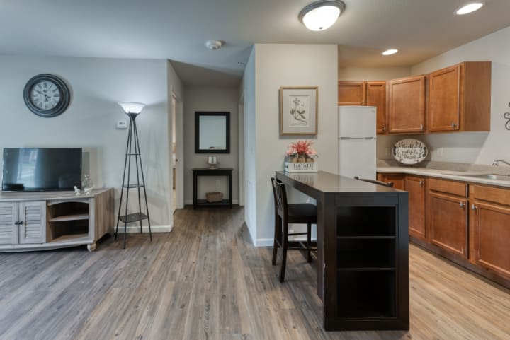 A modern interior featuring a kitchen with wooden cabinets and a dining area, complemented by stylish furniture and a floor lamp.