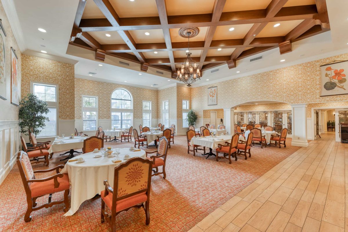 An elegant dining room with beautifully set tables, ornate chairs, and a grand chandelier.