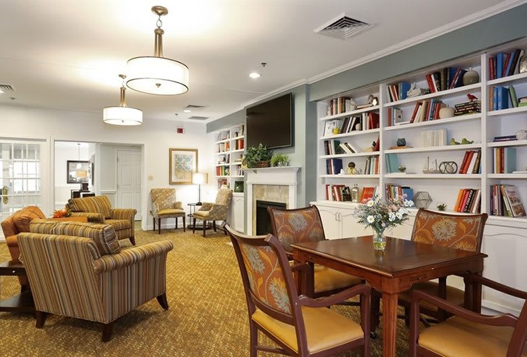 A cozy and modern living room with comfortable seating, bookshelves, and a central table.