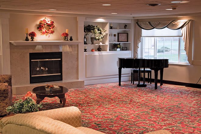 A cozy living room with a fireplace and grand piano.