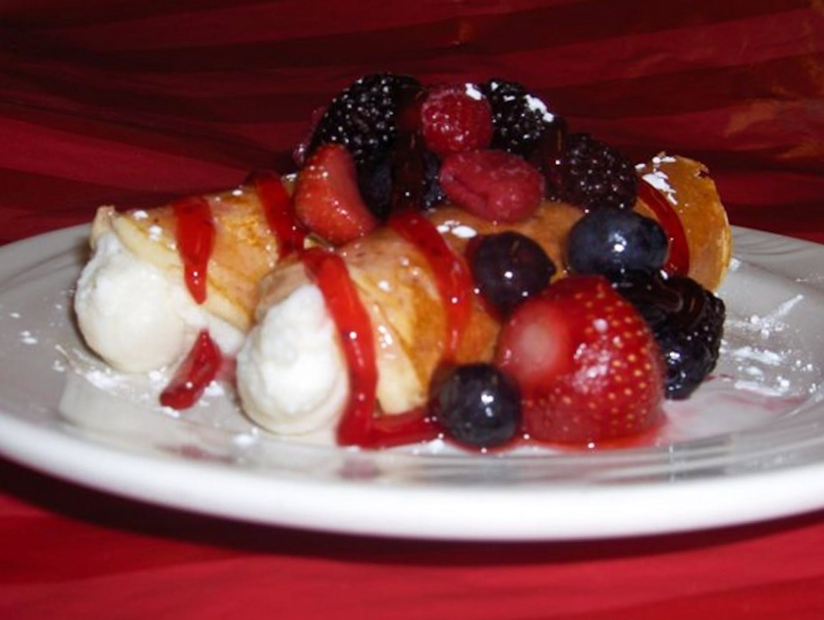 A delicious plate of crepes topped with assorted berries and whipped cream.