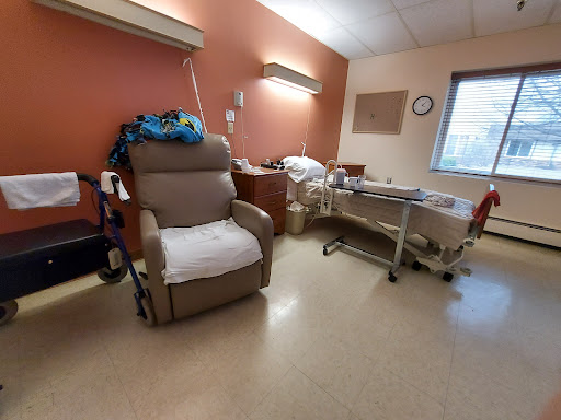 A hospital room featuring a patient bed, a recliner chair, and medical amenities.