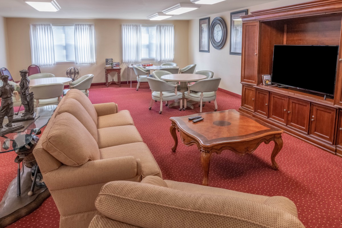 A cozy living room with sofas, a coffee table, and a television, complemented by several tables and chairs.