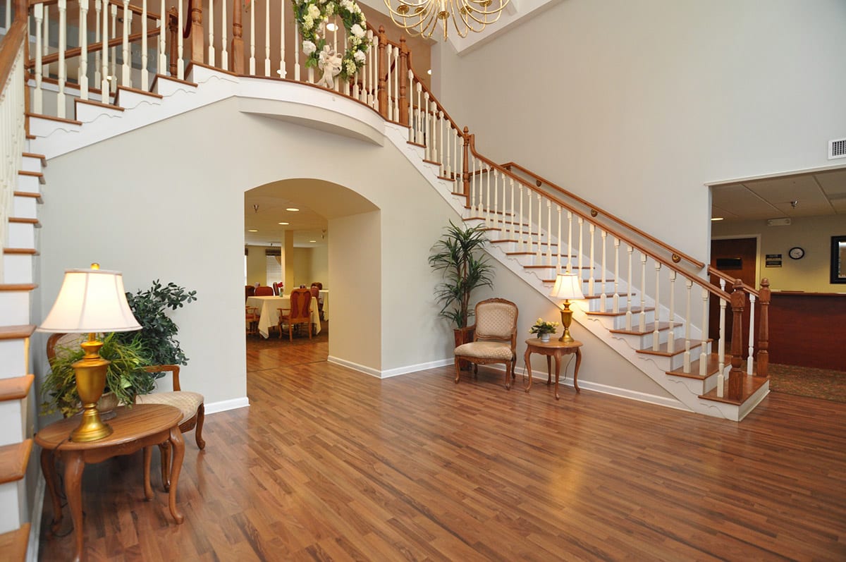A spacious living area featuring a grand staircase and wooden flooring.