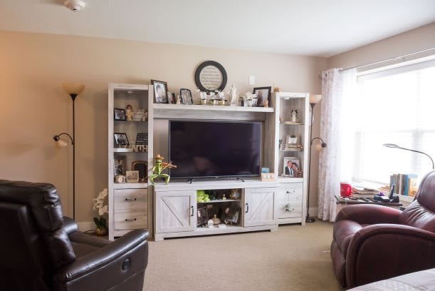 A cozy living room featuring a large entertainment center with a TV and decorative shelves.