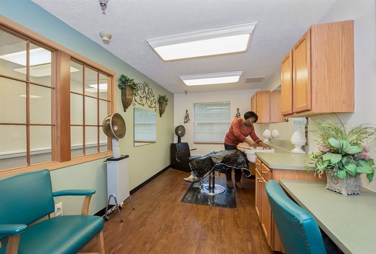 A hair salon interior with a stylist working at a sink station.