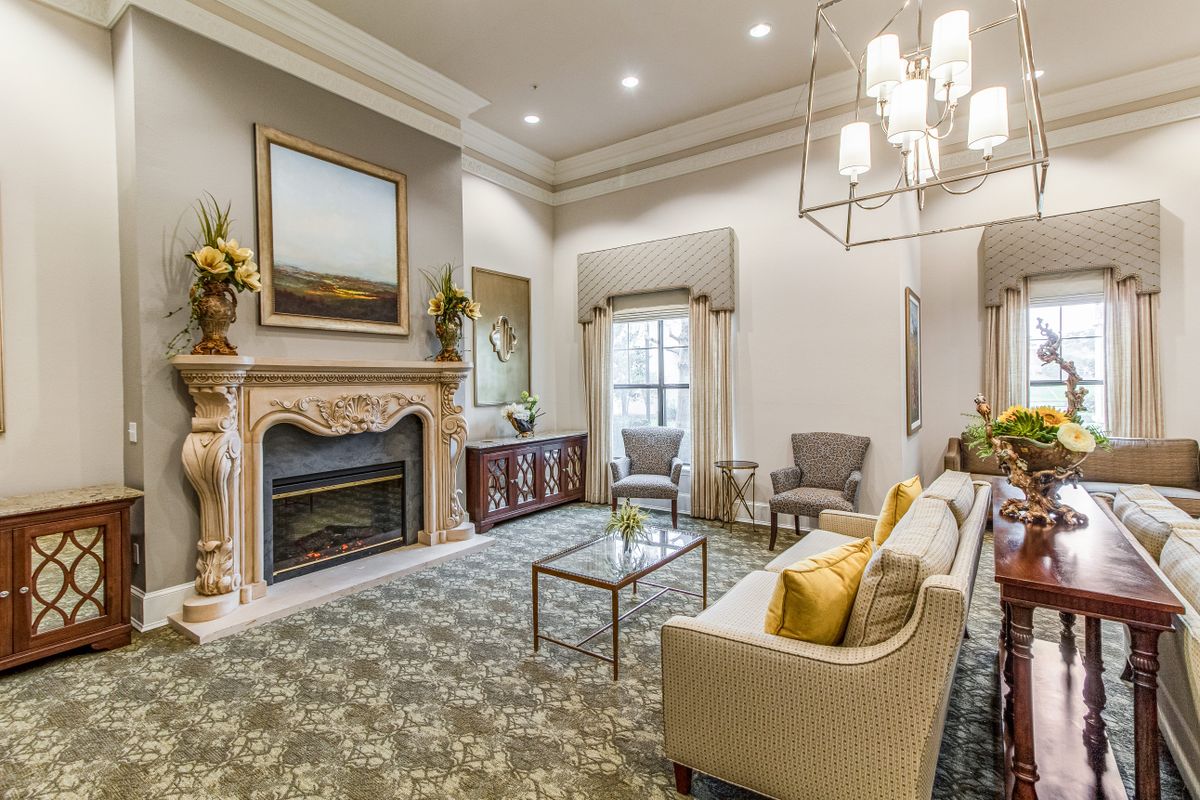 A sophisticated living room featuring an ornate fireplace, elegant furniture, and a modern chandelier.