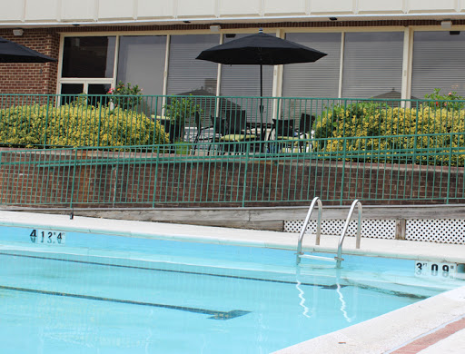A serene outdoor swimming pool area with an umbrella and lounge chairs nearby.