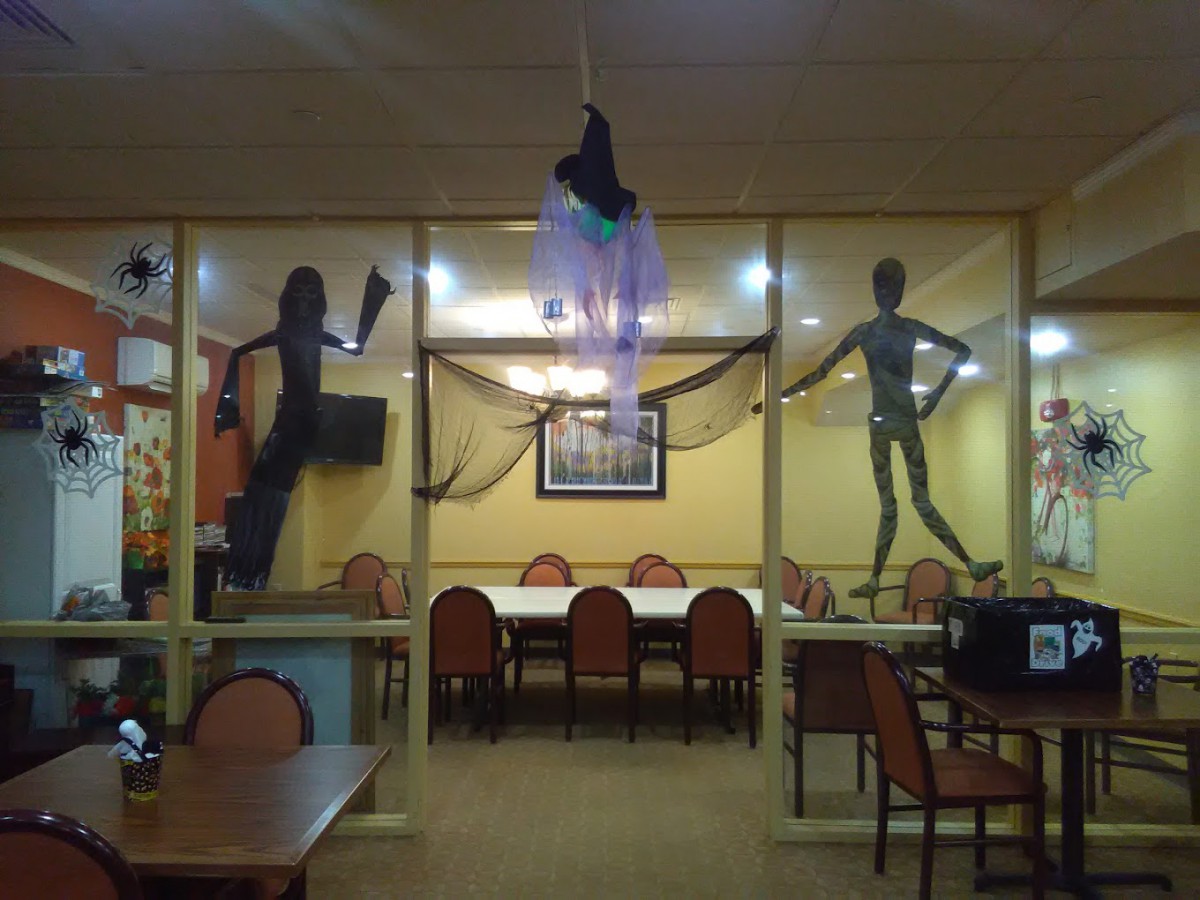 A restaurant decorated for Halloween with ghost and skeleton figures.