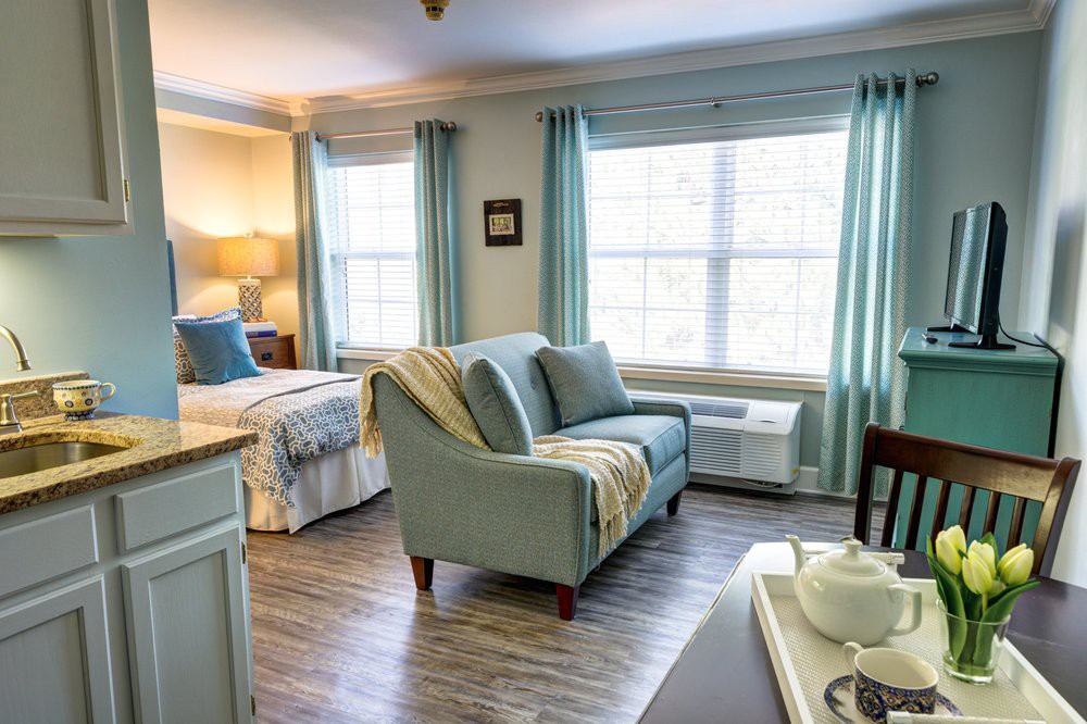 A cozy and well-lit bedroom featuring a comfortable sofa and large windows with curtains.