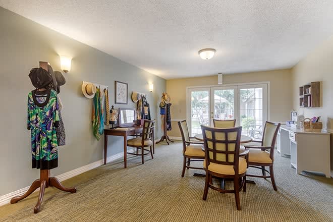 A well-lit dining area featuring a table surrounded by chairs, with decor and large windows.
