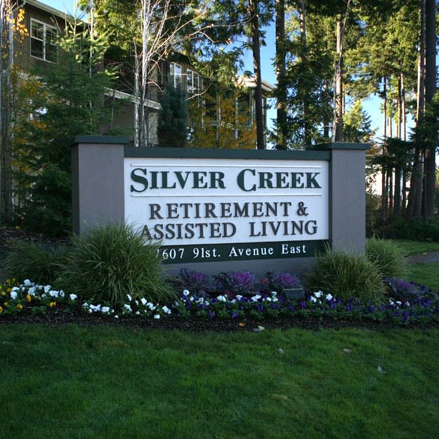 Sign for Silver Creek Retirement & Assisted Living surrounded by greenery.
