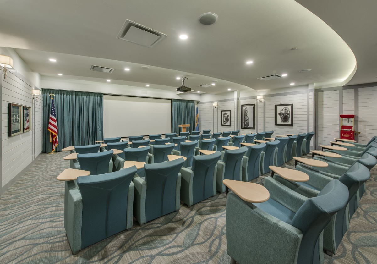 A modern conference room with arranged seating and a large projector screen.