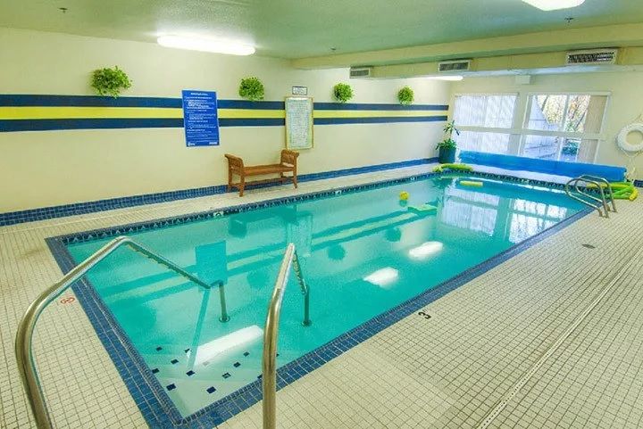 An indoor swimming pool with seating and decor, offering a relaxing atmosphere.