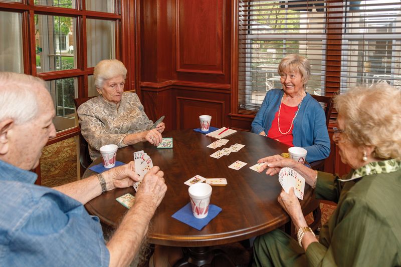 A group of seniors enjoying a card game together indoors.