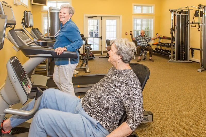 Seniors exercising in a gym with various fitness equipment.