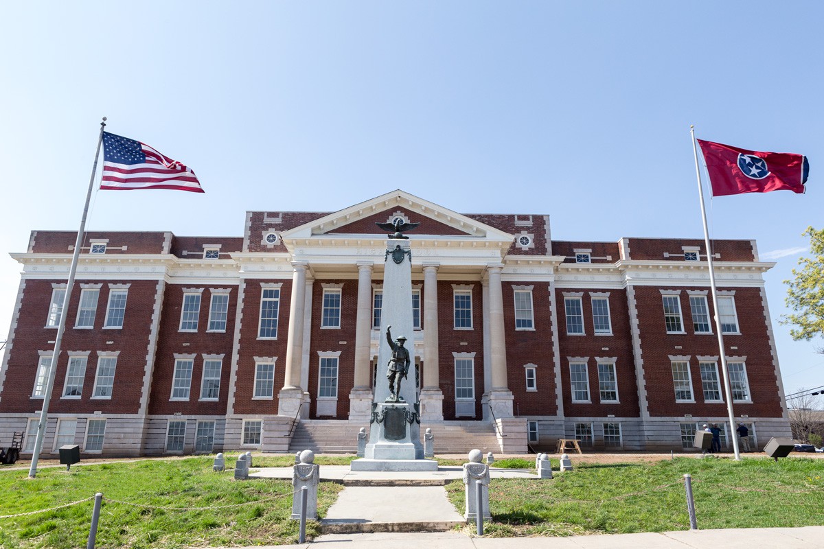 A historic building with columns and a central statue, adorned with an American flag.