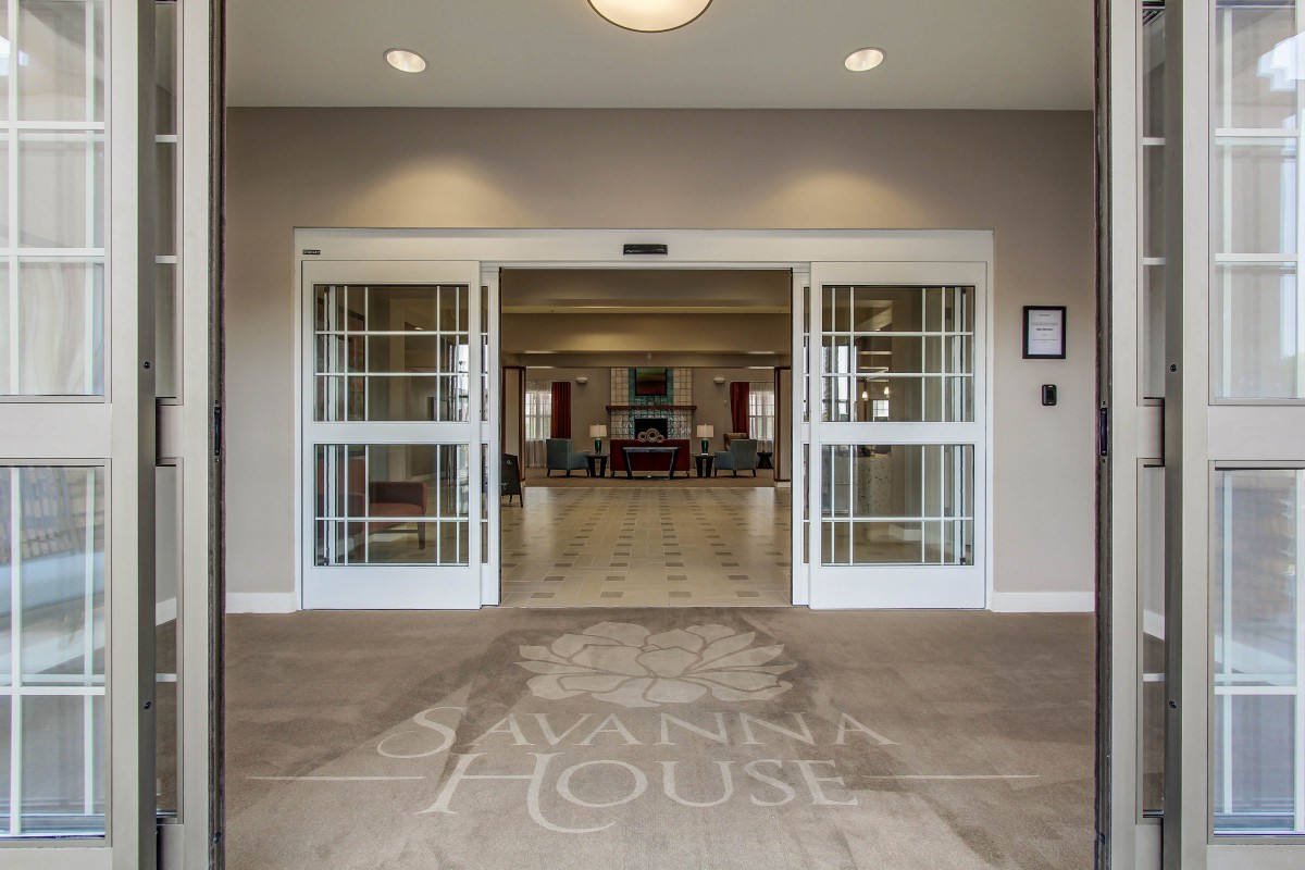 An inviting entrance to a building lobby with open doors and a view of the interior.