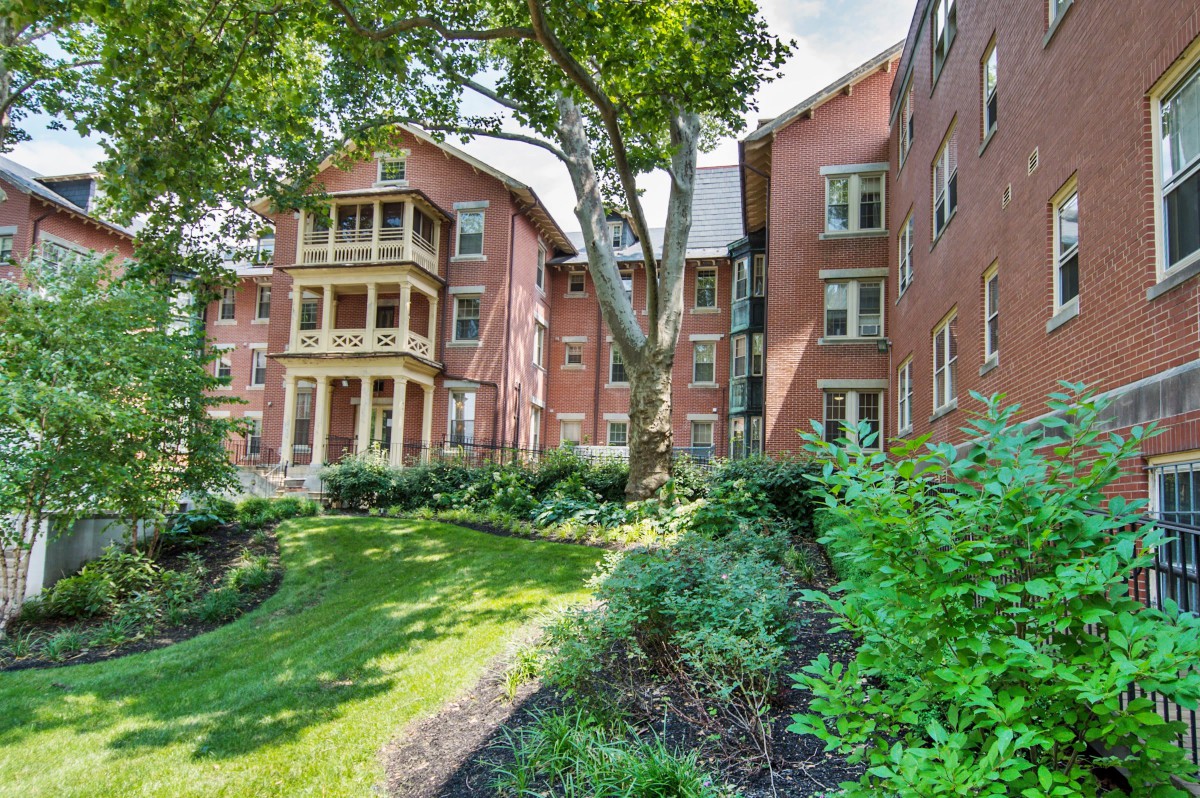 A beautiful brick apartment building surrounded by lush greenery and a garden.