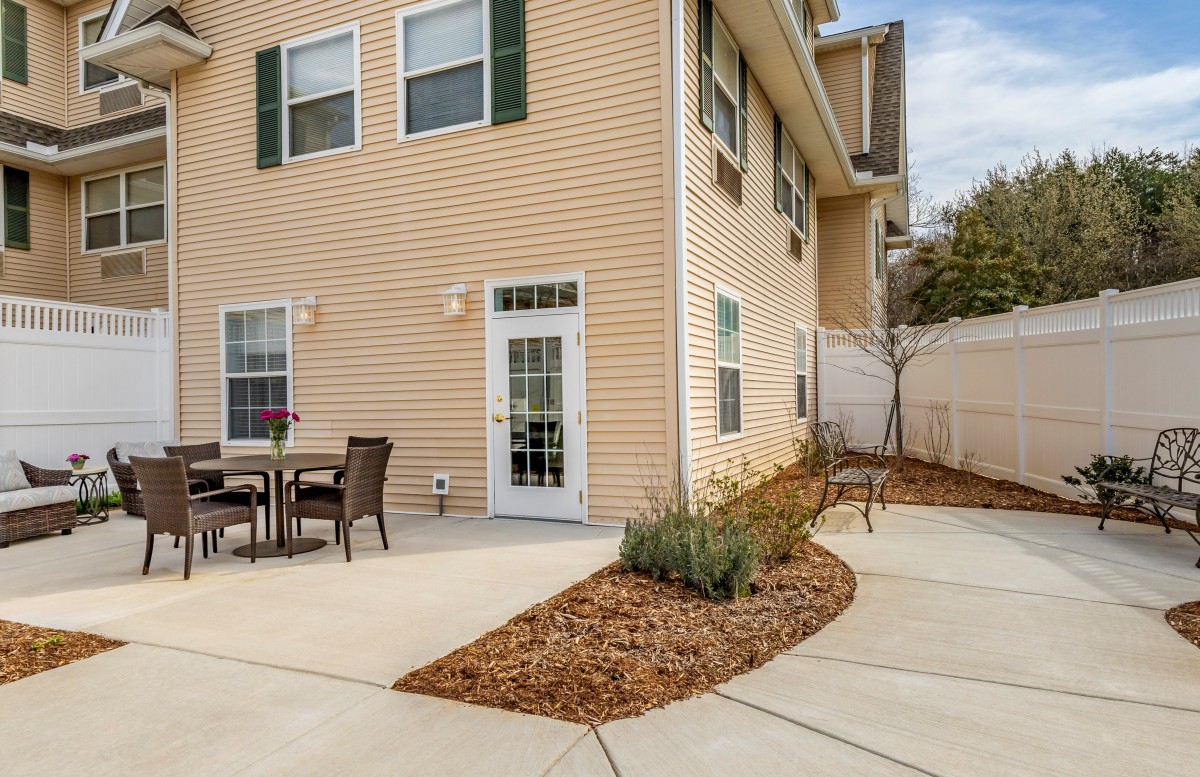 A cozy backyard patio area with a table and chairs, surrounded by landscaping.