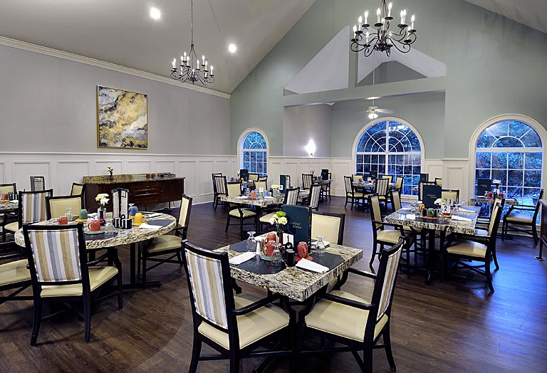 An elegantly designed dining room with chandeliers, featuring neatly arranged tables and chairs.