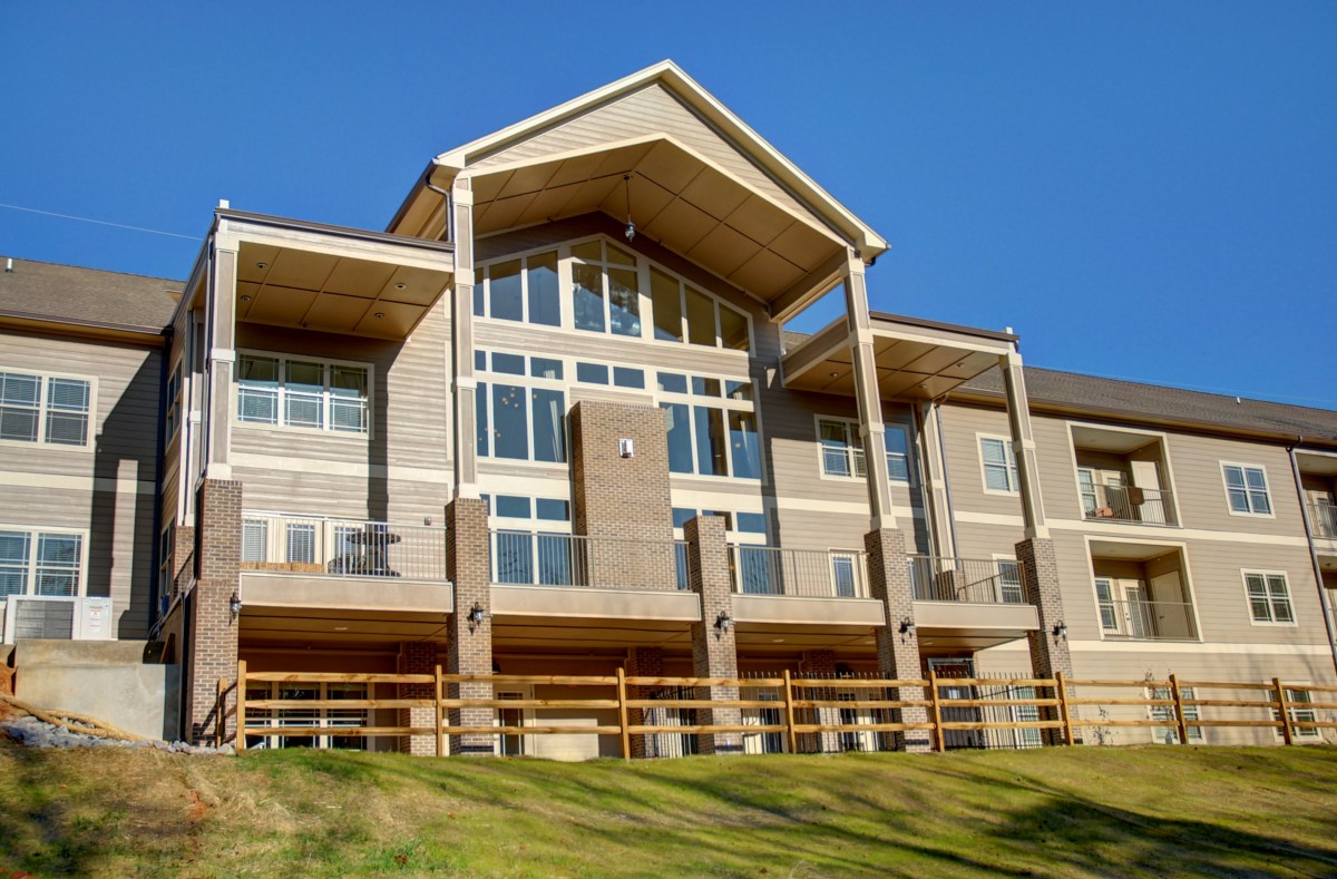 Modern residential building with large windows and a sloped roof.