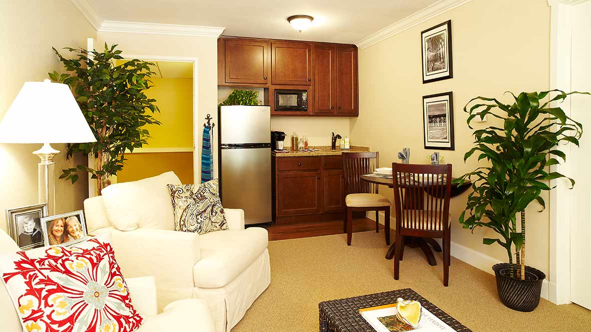 A cozy living space featuring a compact kitchen with wooden cabinets and a small dining area.