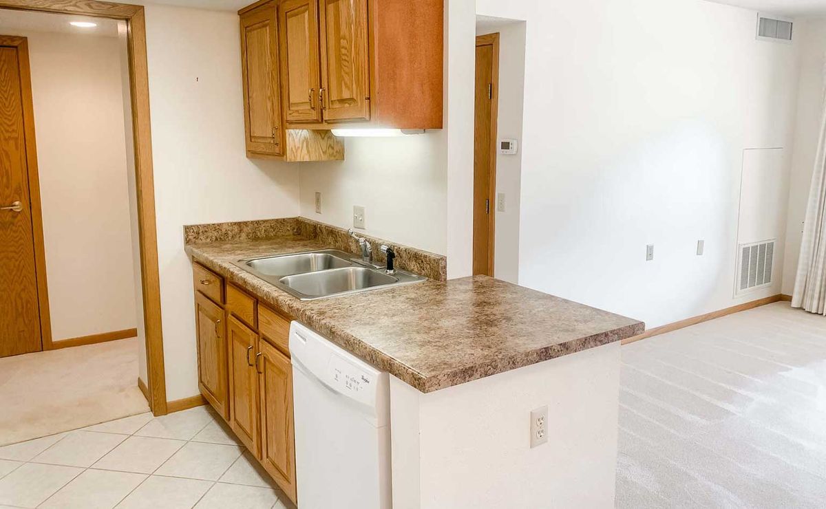 A kitchen with wooden cabinets, a stone countertop, and modern appliances.