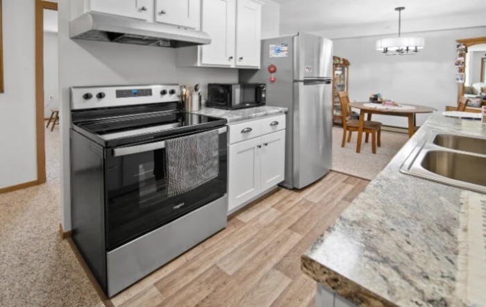 A modern kitchen with stainless steel appliances and a dining area in the background.