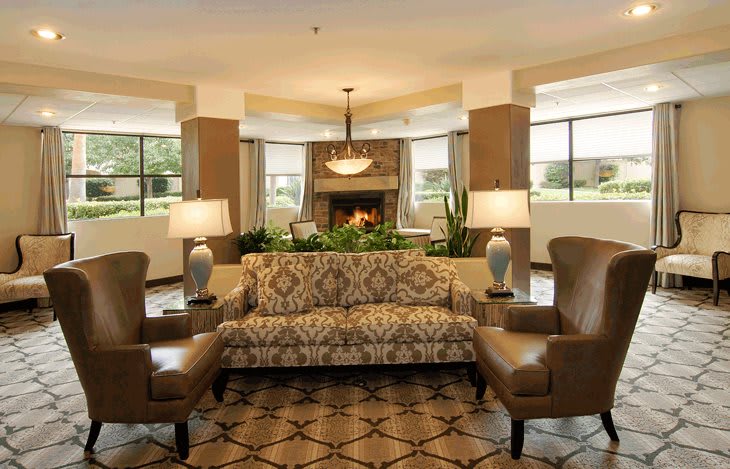 A well-furnished living room with a patterned sofa, armchairs, and decorative lamps.