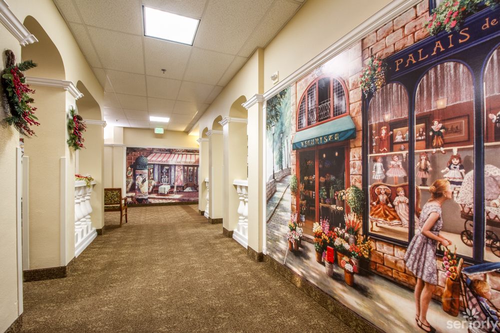 A warmly lit hallway adorned with murals depicting storefronts and urban scenes.