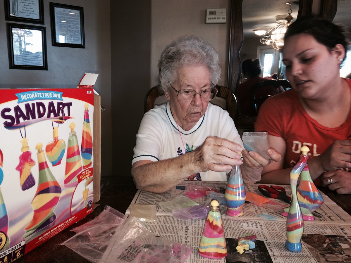 Two people engaged in a sand art craft project at home.