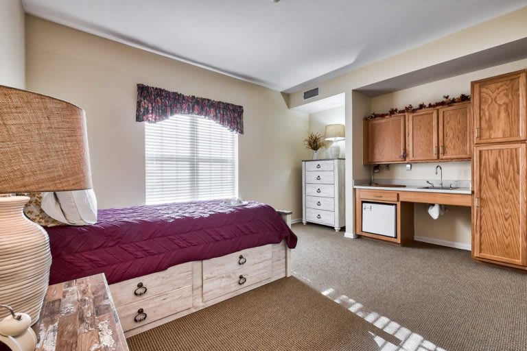 A cozy bedroom with a bed, dresser, and large window with curtains.