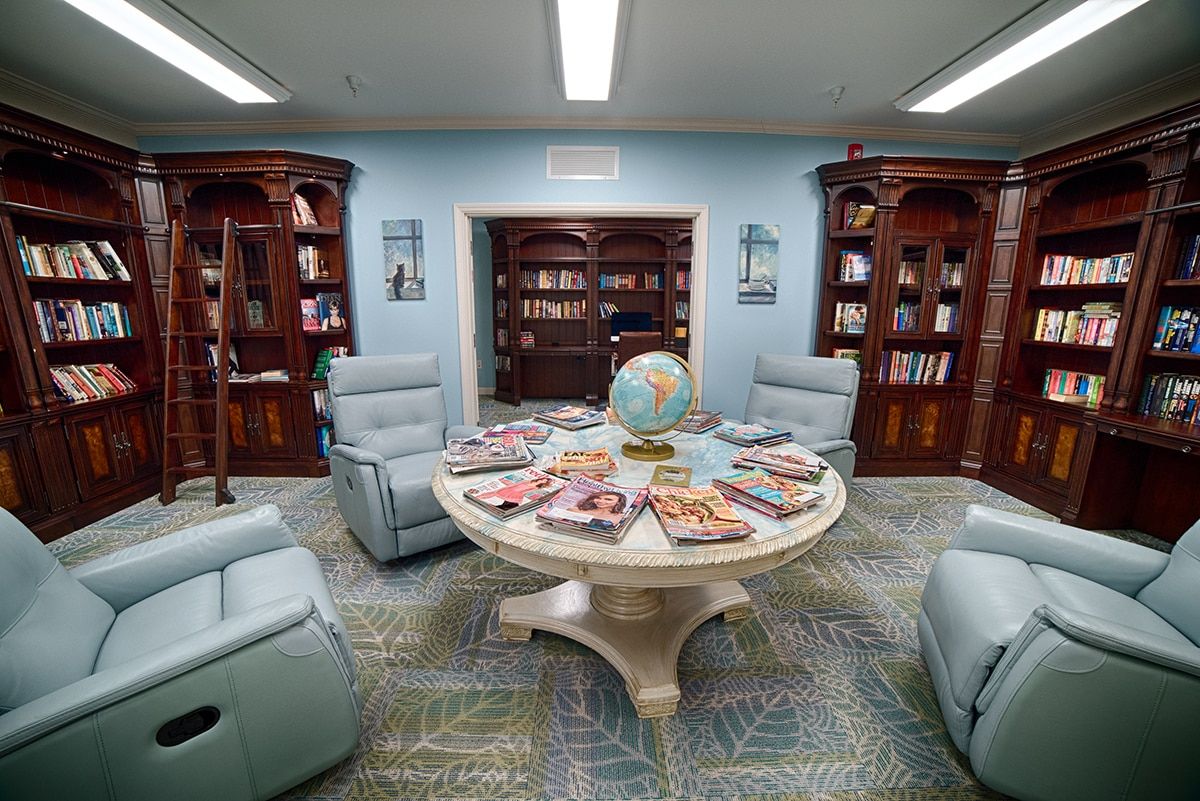 A cozy library reading room with armchairs and a table topped with magazines and a globe.
