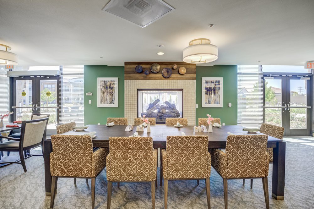A modern dining room featuring a large table with patterned chairs and a fireplace, surrounded by elegant decor.