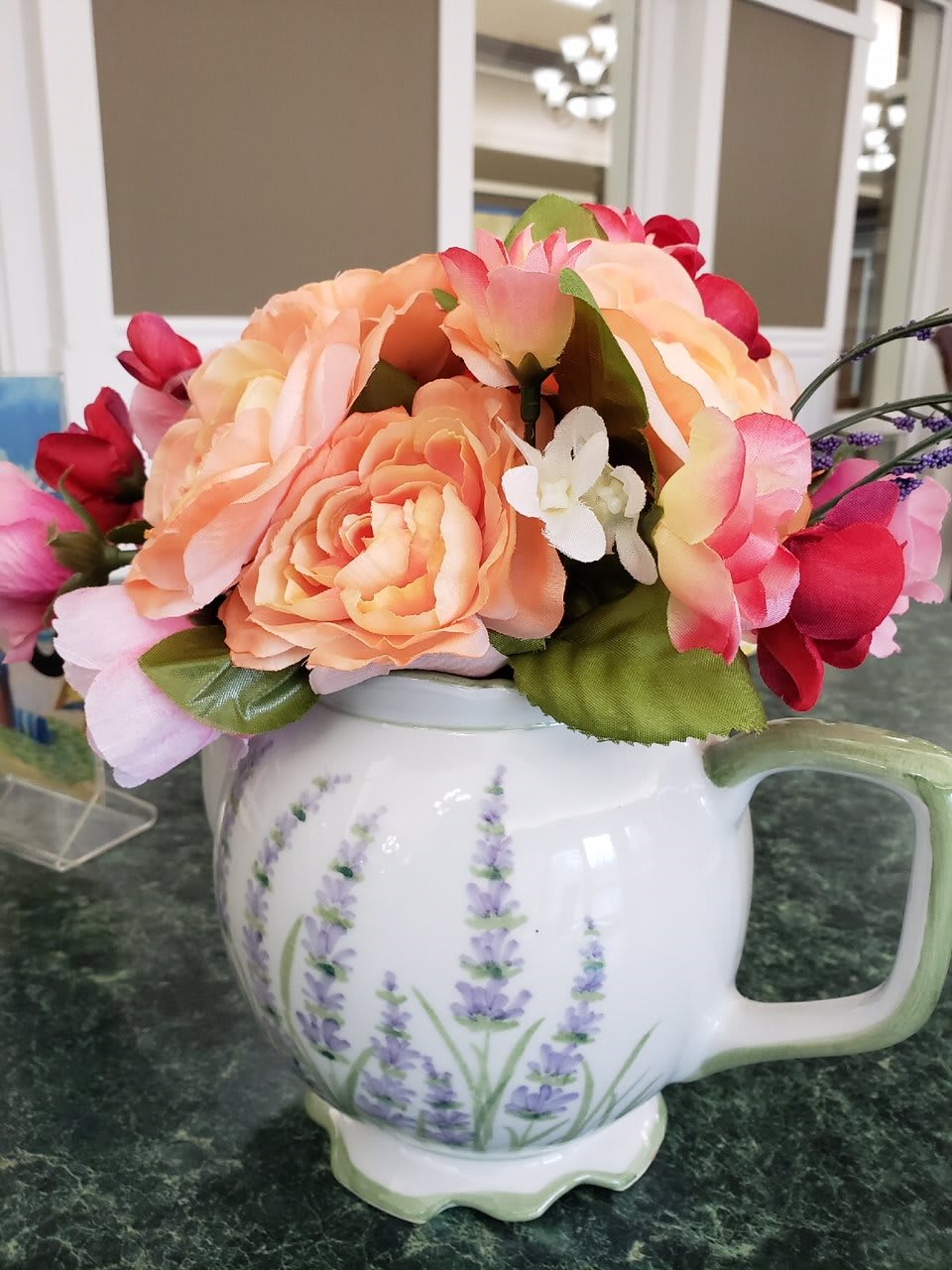 A decorative teapot filled with a vibrant floral arrangement.