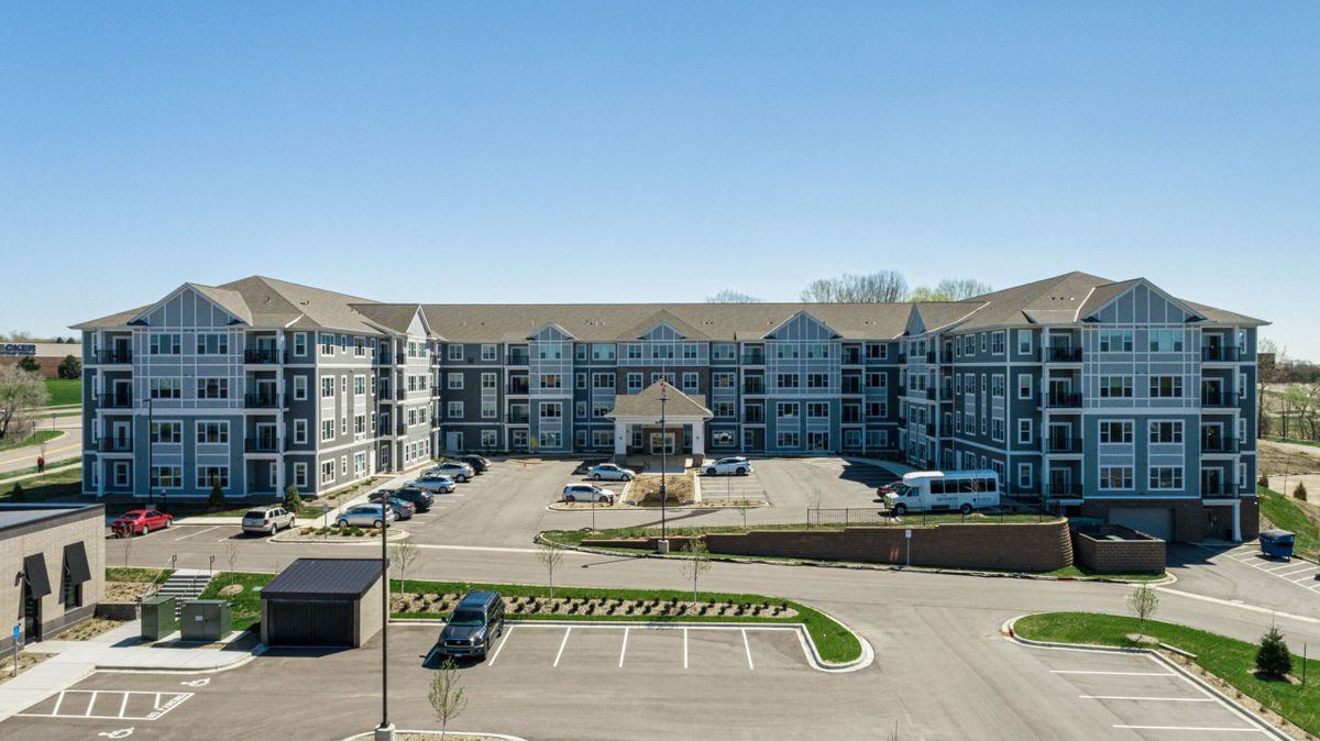 A modern residential apartment complex with a large parking lot in front.
